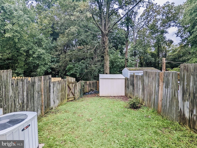 view of yard with a storage shed, an outdoor structure, central air condition unit, and a fenced backyard