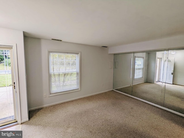 unfurnished bedroom with visible vents, multiple windows, and carpet