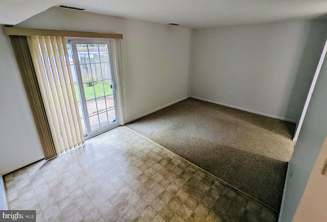 carpeted spare room with tile patterned floors, visible vents, and baseboards