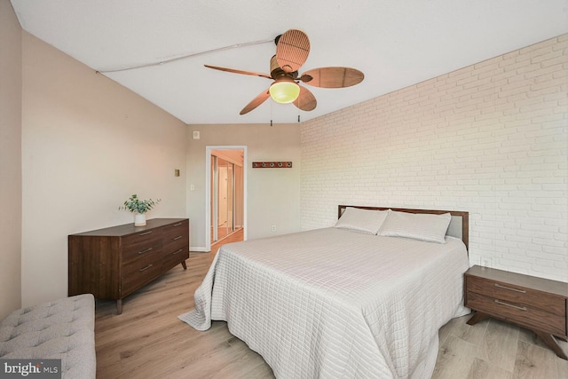 bedroom with brick wall, a ceiling fan, and light wood-style floors