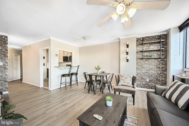 living area with wood finished floors, baseboards, brick wall, and a textured ceiling