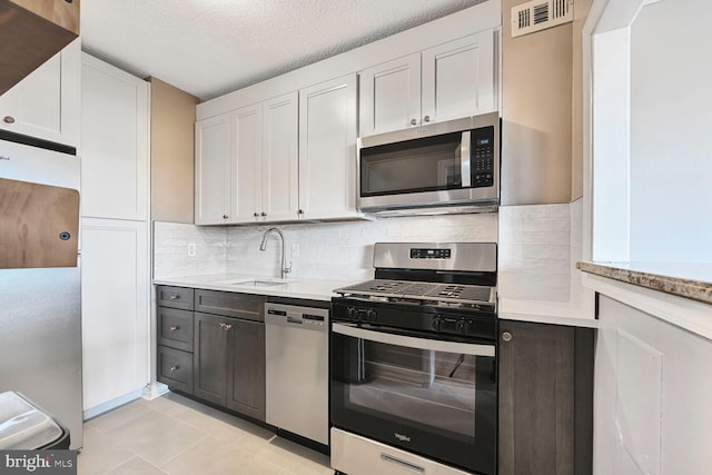 kitchen featuring visible vents, a sink, tasteful backsplash, stainless steel appliances, and light countertops