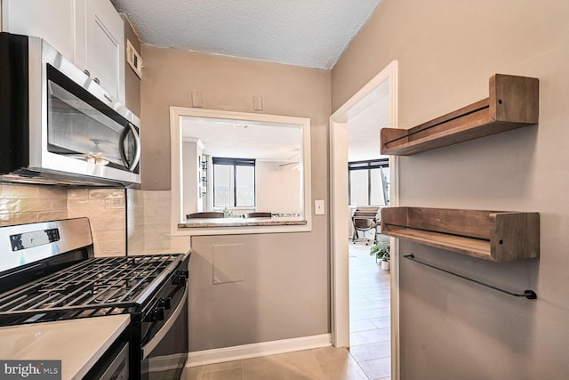 kitchen featuring tasteful backsplash, a healthy amount of sunlight, white cabinets, and stainless steel appliances