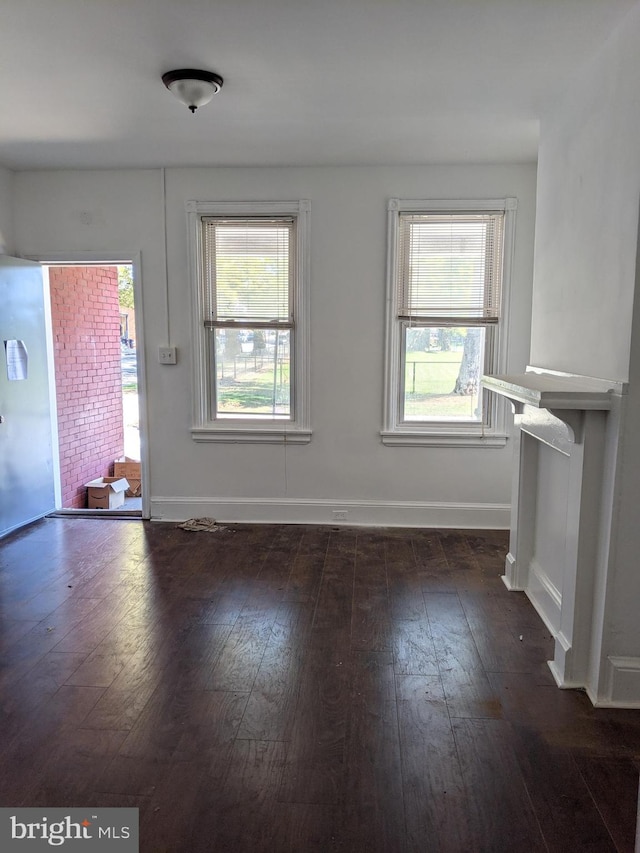 unfurnished living room featuring baseboards and dark wood-style flooring