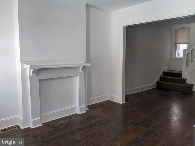 unfurnished living room with visible vents, baseboards, hardwood / wood-style floors, and stairway