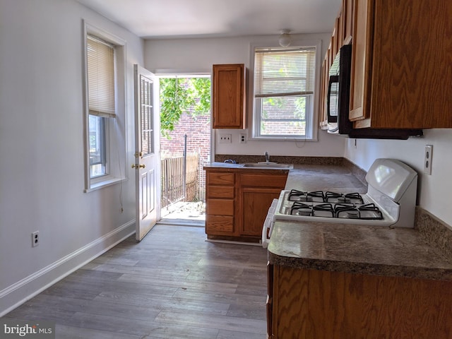 kitchen featuring dark countertops, a sink, black microwave, and white gas range oven