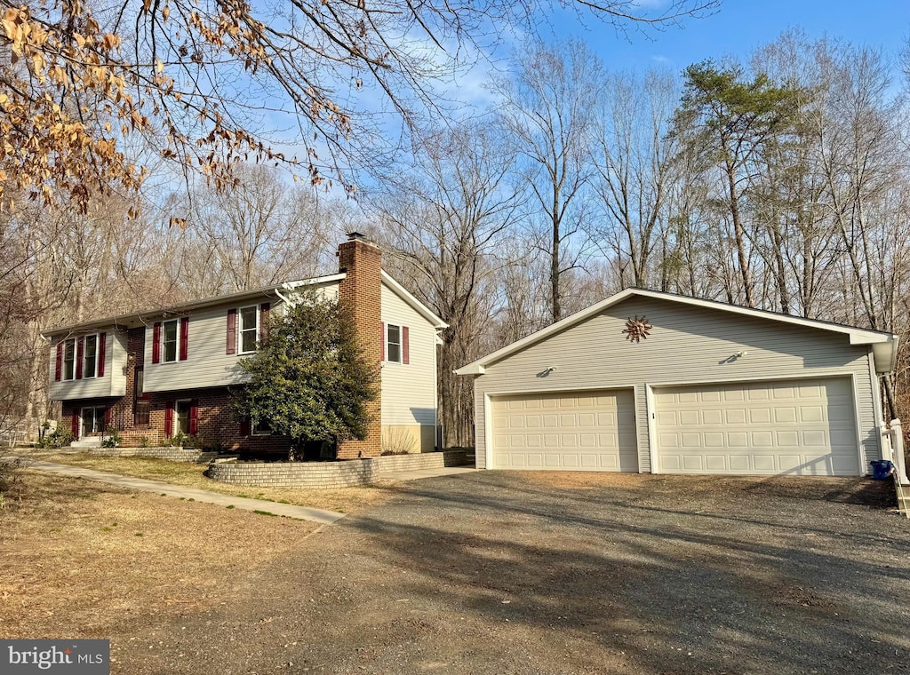 view of side of home with a garage, a chimney, and an outdoor structure