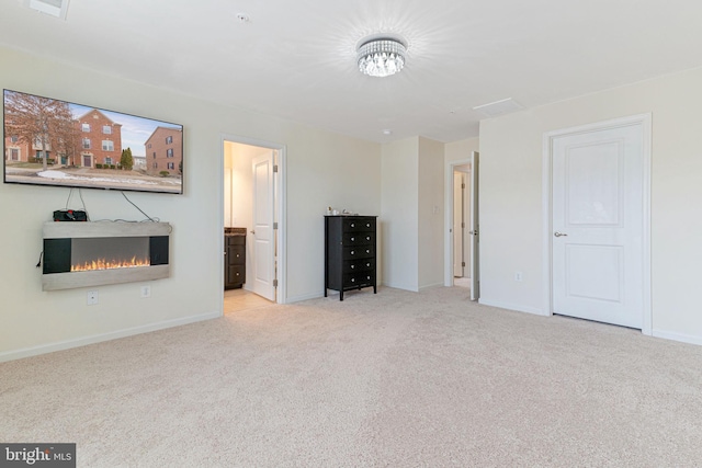 unfurnished living room with baseboards, a warm lit fireplace, and carpet flooring