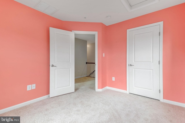 unfurnished bedroom with baseboards, visible vents, attic access, and carpet