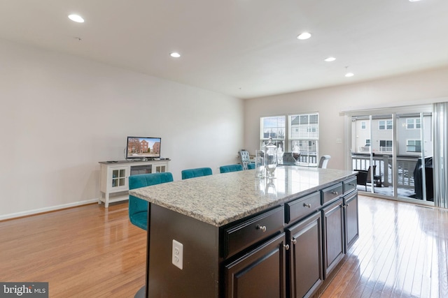 kitchen featuring a center island, recessed lighting, light wood-style flooring, and a breakfast bar