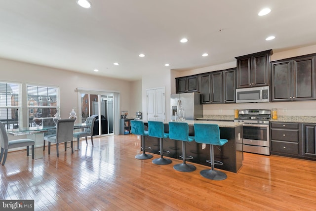 kitchen with recessed lighting, stainless steel appliances, a kitchen island, and light wood-style flooring