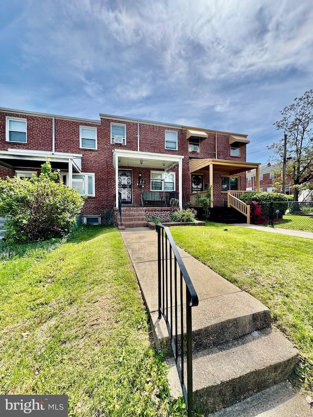 view of front of property with a front yard, a porch, brick siding, and fence