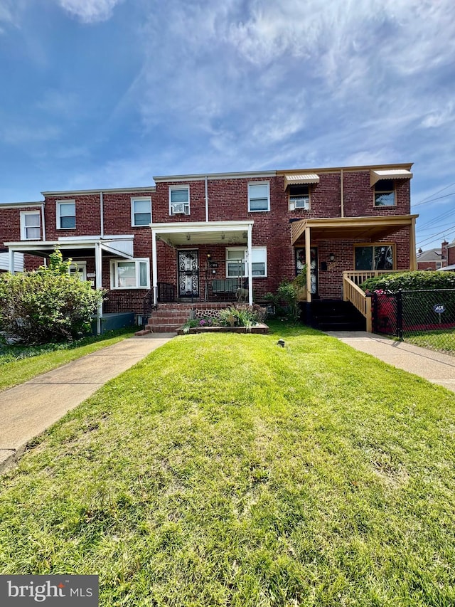 townhome / multi-family property with brick siding, fence, and a front yard