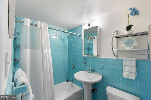 full bathroom with tile walls, toilet, shower / bath combo, and wainscoting