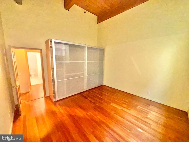 unfurnished bedroom with beam ceiling and wood finished floors