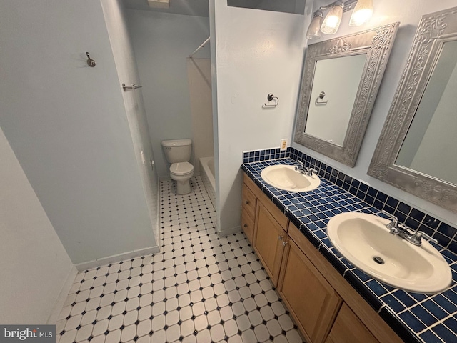 bathroom featuring double vanity, backsplash, toilet, and a sink