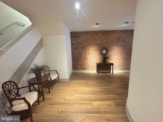 hall featuring recessed lighting, brick wall, baseboards, and light wood-style floors