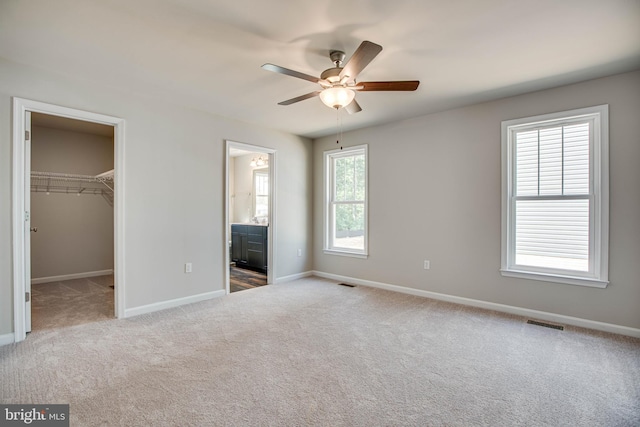 unfurnished bedroom with visible vents, carpet flooring, a walk in closet, and baseboards