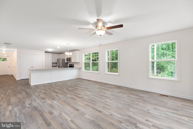 unfurnished living room featuring visible vents, a ceiling fan, light wood-style floors, and baseboards