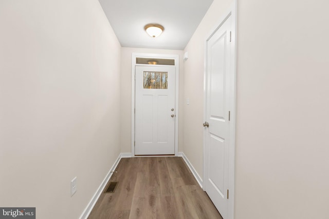 doorway featuring visible vents, baseboards, and wood finished floors