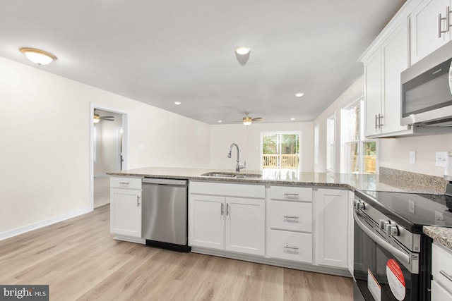 kitchen featuring appliances with stainless steel finishes, light wood-type flooring, a ceiling fan, and a sink