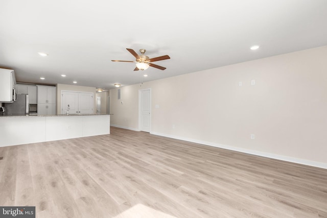 unfurnished living room with recessed lighting, a ceiling fan, light wood-type flooring, and baseboards