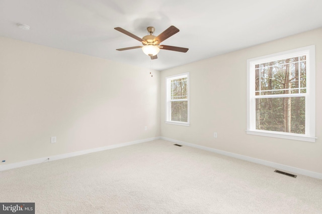 carpeted empty room with visible vents, baseboards, and a ceiling fan