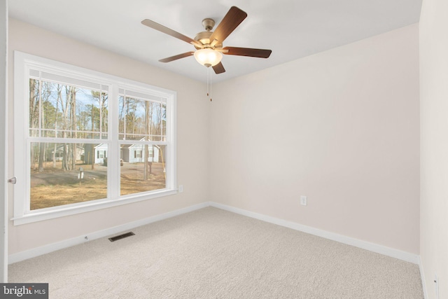 carpeted empty room with visible vents, baseboards, and a ceiling fan