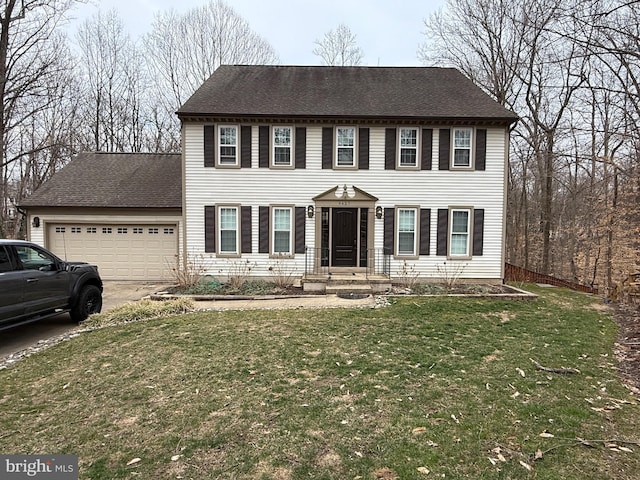 colonial inspired home with a front lawn, an attached garage, driveway, and a shingled roof