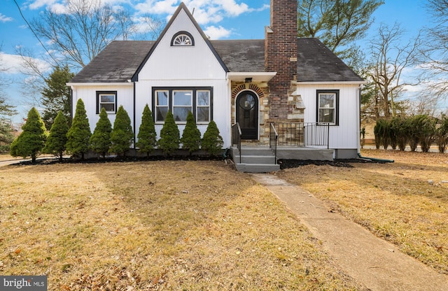 tudor-style house featuring a front yard and a chimney