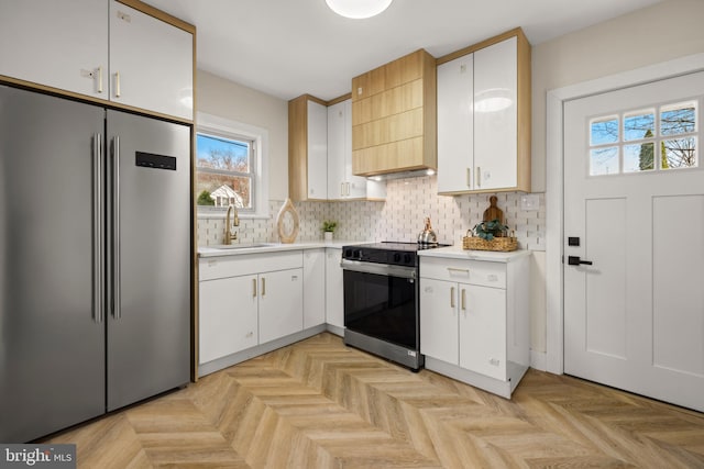 kitchen with electric range, a sink, light countertops, high quality fridge, and backsplash