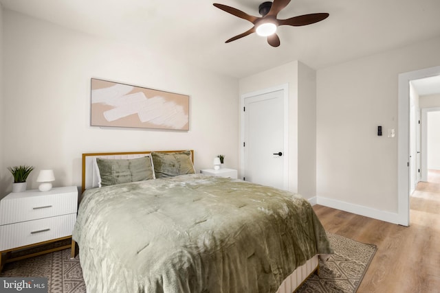 bedroom with ceiling fan, baseboards, and wood finished floors