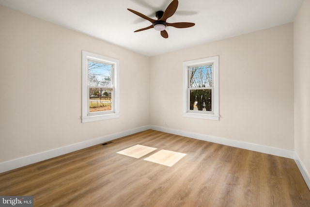 spare room with visible vents, baseboards, wood finished floors, and a ceiling fan