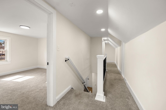 hallway featuring baseboards, an upstairs landing, carpet, and vaulted ceiling