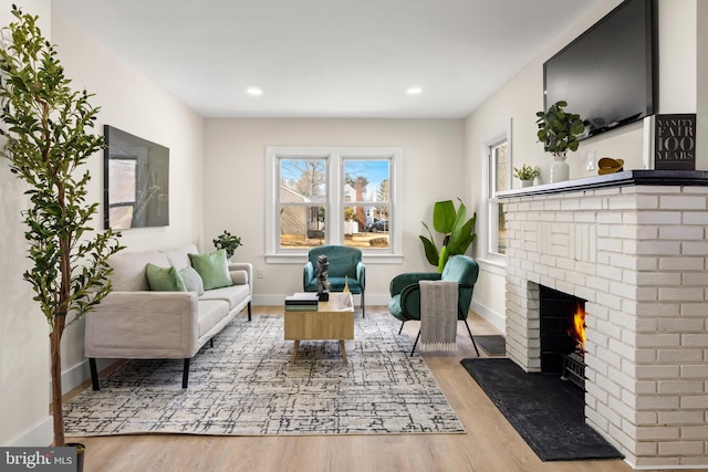 living area featuring recessed lighting, baseboards, a brick fireplace, and wood finished floors