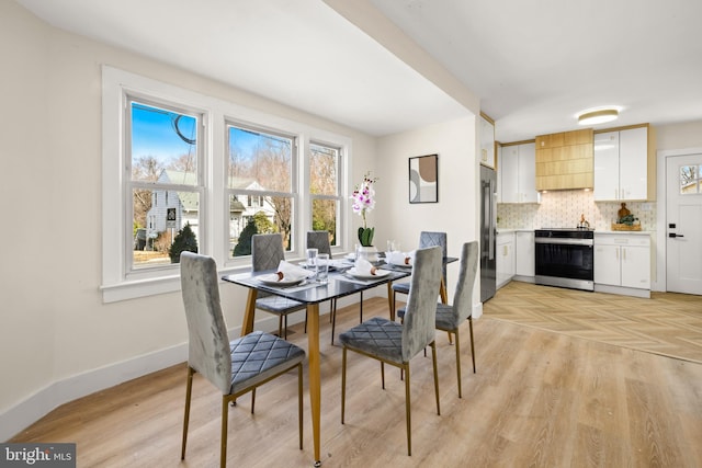 dining space featuring baseboards and light wood-type flooring