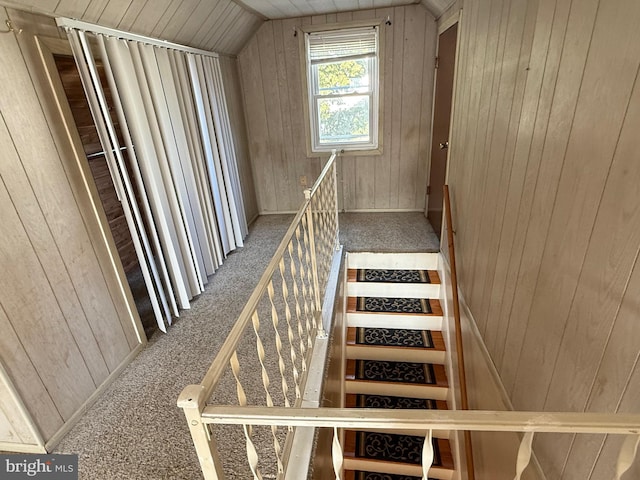 staircase with wooden walls, carpet flooring, and vaulted ceiling