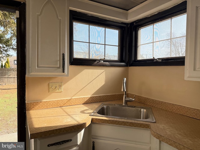 kitchen with light countertops, white cabinets, and a sink