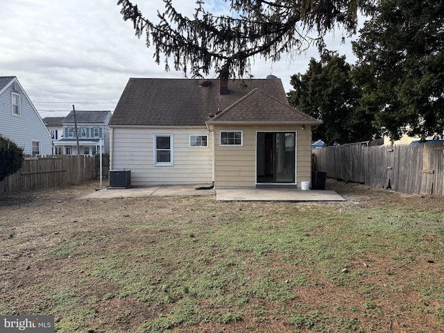 rear view of property with roof with shingles, cooling unit, a fenced backyard, a yard, and a patio