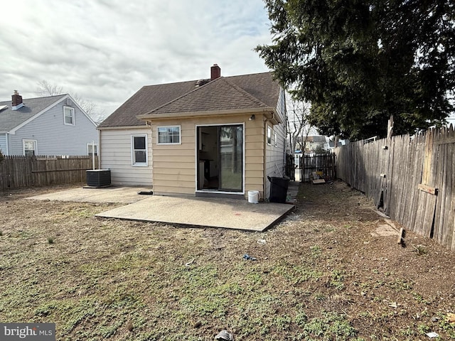 back of property featuring cooling unit, a fenced backyard, a chimney, a shingled roof, and a patio area