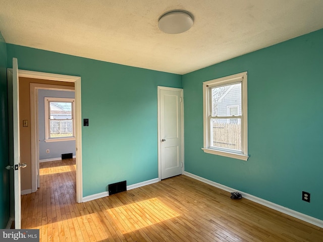 unfurnished bedroom featuring baseboards, a textured ceiling, and hardwood / wood-style floors