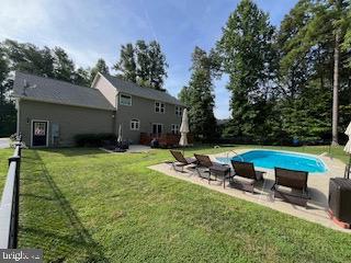 back of house featuring a patio area, a lawn, and an outdoor pool