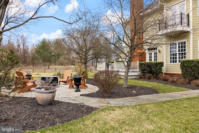 view of yard featuring a patio area, a wooden deck, a fire pit, and fence