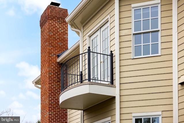 view of property exterior with a chimney and a balcony