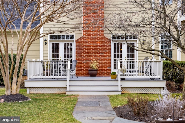 view of exterior entry with french doors and a chimney