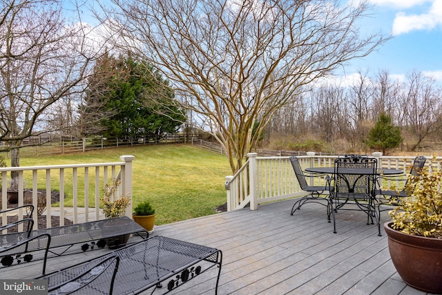 deck featuring outdoor dining area, a lawn, and a fenced backyard