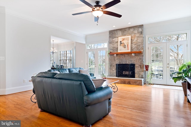 living room with ceiling fan with notable chandelier, wood finished floors, french doors, crown molding, and baseboards