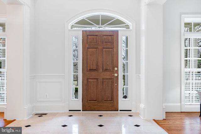 tiled entrance foyer featuring a wealth of natural light and a decorative wall