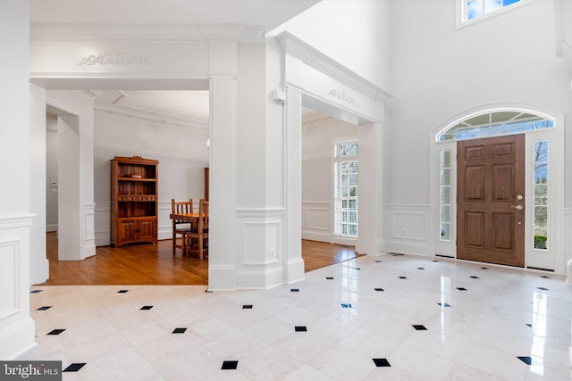 foyer entrance with wainscoting, crown molding, and a decorative wall