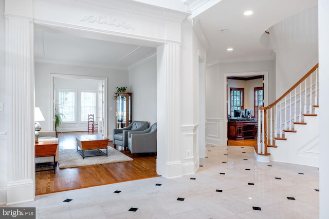 entryway featuring a decorative wall, wainscoting, and crown molding